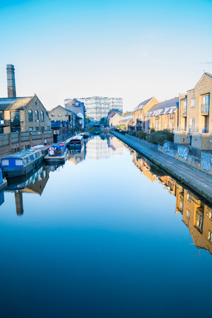 LONDON, ENGLAND  - AUGUST 6, 2017; Hertford Union Canal calm in eary moring light with house boats moored alongside and apartment opposite at Bow Wharf, East London, UKのeditorial素材