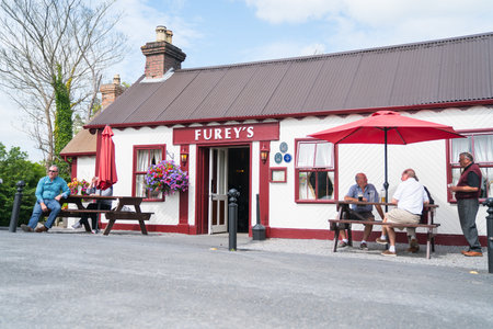 TRIM, IRELAND - AUGUST 11, 2017; group of local men sit under umbrella drinking beer outside Furey's...