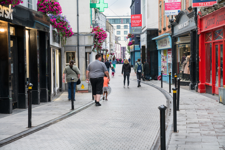 WEXFORD, IRELAND - AUGUST 14, 2017; Family walking in Irish small town narrow street between rows of shop and traditional shop fronts.のeditorial素材
