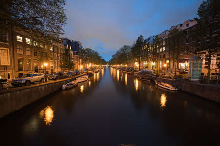 AMSTERDAM, HOLLAND - AUGUST 21, 2017; Magical effect of night lights in zoom blur reflected in calm water of Amsterdam canal lined with typical buildingsのeditorial素材