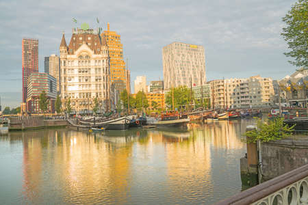 ROTTERDAM, HOLLAND- AUGUST 23, 2017;  sun rises and catches buildings across canal and shadows old style boats moored beneath the Gothic style building known as Whitehouseのeditorial素材