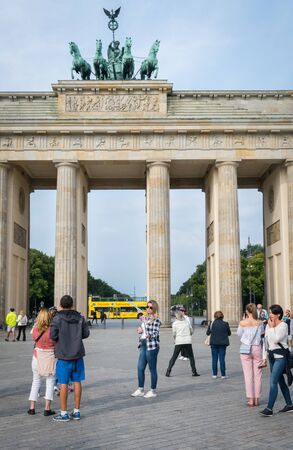 BERLIN, GERMANY - AUGUST 25, 2017; Tourist mingle about while woman takes selfie in front of Brandenburg Gate a neo-classical architecture and bronze statue four hourses pulling chariot on topのeditorial素材
