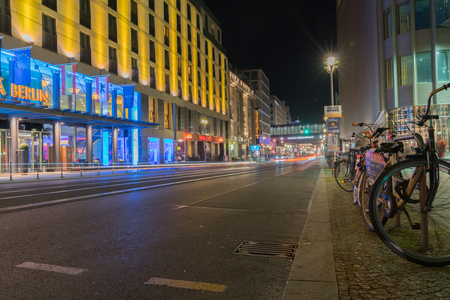 BERLIN, GERMANY - AUGUST 26, 2017;  Long exposure night image Friedrichestrasse retail shops line both sides of street with light streams from passing vehicles  reflecting off tram lines down center of road and hire bikes on right.のeditorial素材