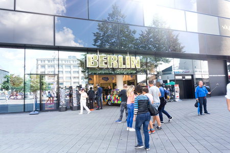 BERLIN, GERMANY -AUGUST 28, 2017; Curious tourists and passers-by on street in Alexandra Platz in front of shop of interesting object under big BERLIN sign.のeditorial素材