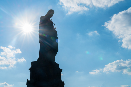 Silhouette statue of Saint Joseph with Christ as child back-lit by sun on Charles Bridge.の写真素材