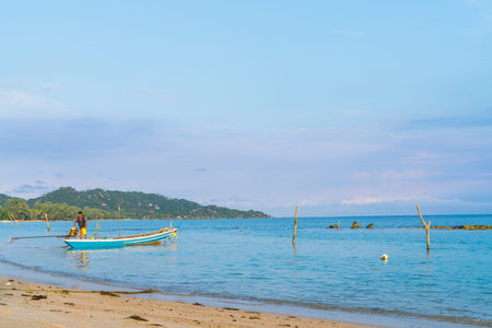 KO SAMUI, THAILAND - JANUARY, 23, 2018; Asian idyllic picturesque coastal scene with traditional long tail fishing boat with fisherman fueling motor.のeditorial素材