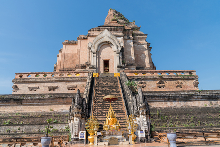Gold Buddha statue with donation boxes at foot of steps of large brick structure of Wat Chedi Luang temple remains in Chiang Mai Thailandのeditorial素材