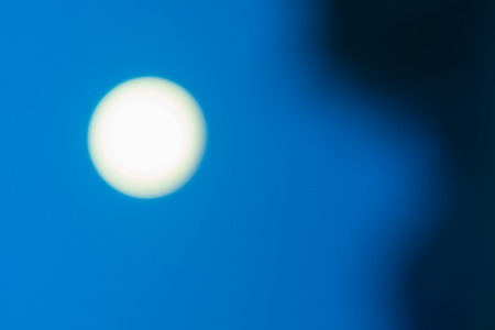 Sky  background dark shadow on right and large new sun glowing against blueの写真素材