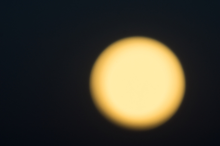 Golden glow of full moon against black night sky.の写真素材