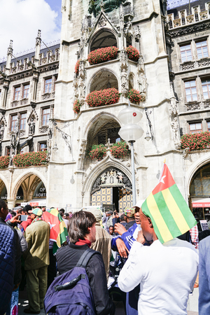 MUNICH, GERMANY - SEPTEMBER 8 2017; Togo flag held at back of crowd protestors marching through tourists in city central square below the gothic city hall.のeditorial素材