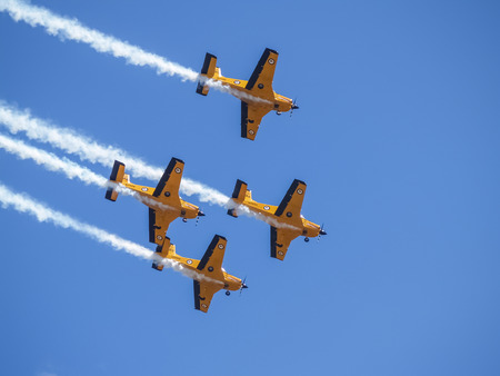 TAURANGA NEW ZEALAND - FEBRUARY 17, 2008; Four yellow vintage New Zealand airforce trainer planes fly past in formation with vapor trails against blue sky.のeditorial素材