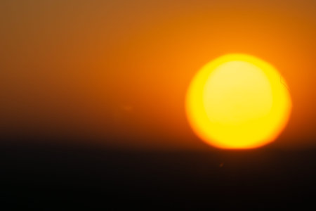 Golden sky illuminated by large round setting sun  at end of day in Namibia.