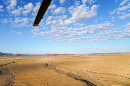 Aerial landscape, wide flat  area stretching to horizon with helicopter rotor blade  from tourist helicopter flight over Sossusvlei Namibia.の写真素材