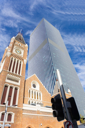 PERTH AUSTRALIA - MAY 30 2018;  Contrasting modern architecture of brutalist modernist style highrise office building and traditional red brick church from low angle point of view.のeditorial素材