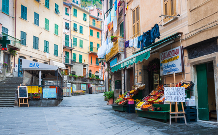 RIOMAGGIORE, ITALY - APRIL 25 2011; Village street between high traditional buildings scene with bar, food and fruit and vegetable shop in Cinque Terre.のeditorial素材
