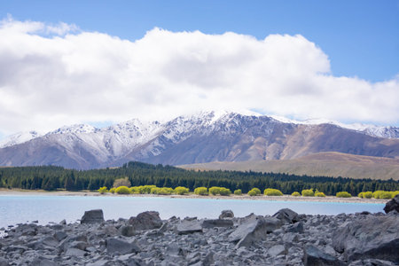 Ruataniwha Inlet foreshore at low tide with snow on top distant mountains under dramaitc clouds at...