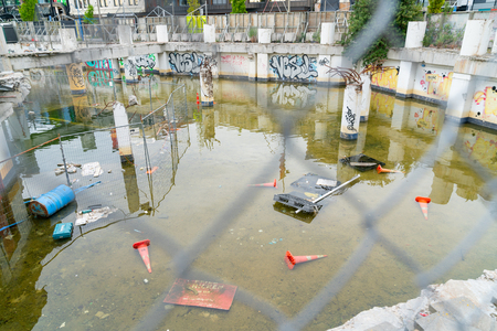 CHRISTCHURCH NEW ZEALAND OCTOBER 10 2018; Deserted remains of commercial building foundations flooded left for reconstruction in Christchurch after the earthquake with graffiti and rubbish looking through fenceのeditorial素材