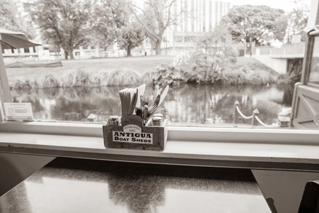 CHRISTCHURCH, NEW ZEALAND - OCTOBER 10 2018; Looking through Antigua Boat Sheds restaurant window to river and city in sepia, old-fashioned photo.のeditorial素材