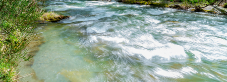 Arrow River flowing fast through gorge lined with lush green deciduous treesの写真素材