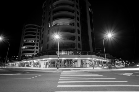MOUNT MAUNGANUI NEW ZEALAND - FEBRUARY 7 2019: Apartments and cafes Marine Parade corner at base of mount street illuminated by street lightsのeditorial素材