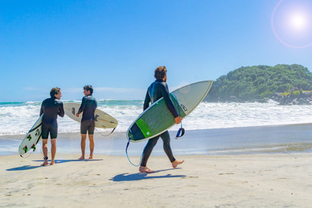 MOUNT MAUNGANUI NEW ZEALAND - FEBRUARY 10 2019:  Surfers walk the Main Beach looking for best spot...
