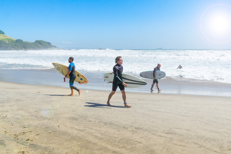 MOUNT MAUNGANUI NEW ZEALAND - FEBRUARY 10 2019:  Surfers walk the Main Beach looking for best spot to enteron a rough sea day.のeditorial素材