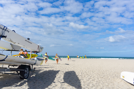 MOUNT MAUNGANUI NEW ZEALAND - FEBRUARY 8 2019: Members Mount Maunganui Surf Lifesavers club head down beach carrying paddleboards to surf.のeditorial素材