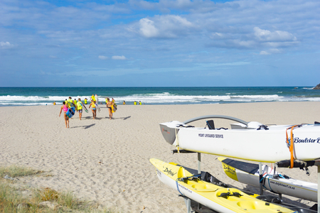 MOUNT MAUNGANUI NEW ZEALAND - FEBRUARY 8 2019: Members Mount Maunganui Surf Lifesavers club head down beach carrying paddleboards to surf.のeditorial素材