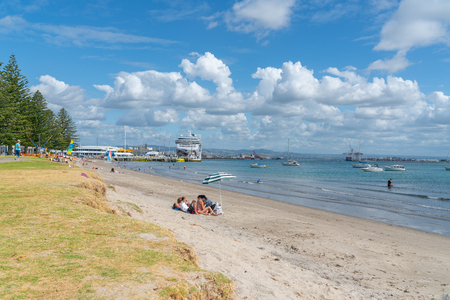 MOUNT MAUNGANUI NEW ZEALAND - FEBRUARY 8 2019: Cruise ship Norwegian Jewel berthed at Mount wharf at end of Pilot Baywhile people enjoy afternoon sun and beach activitiesのeditorial素材