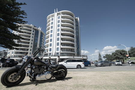 MOUNT MAUNGANUI NEW ZEALAND - FEBRUARY 10 2019: Cruiser motorbike parked on berm at Mount Main Beach with Oceanscide twin Towers background.のeditorial素材