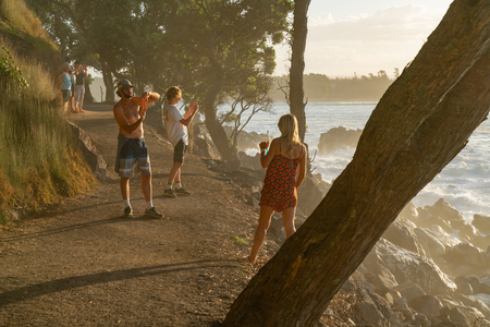 MOUNT MAUNGANUI NEW ZEALAND - FEBRUARY 10 2019: Base track popular walk with people walking and photographing caught in enening suns rays and spray off sea.のeditorial素材