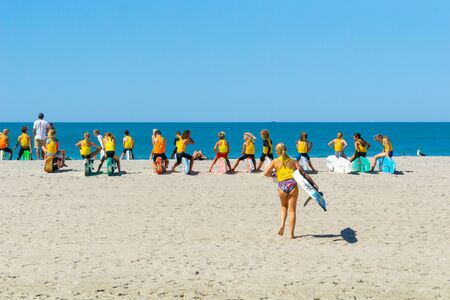 TAURANGA NEW ZEALAND FEBRUARY 12 2019; Girl carrying board walks toward group young club members lined up and waiting on beachのeditorial素材