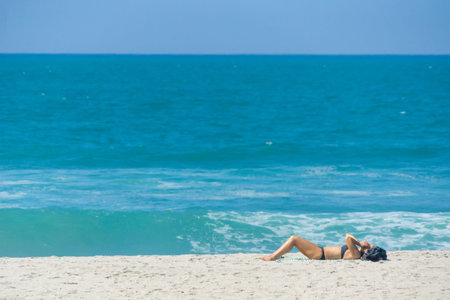TAURANGA  NEW ZEALAND - FEBRUARY 14 2019; Lone sunbather on Mount Maunganui ocean beach near water's...