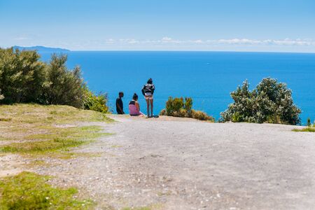 TAURANGA NEW ZEALAND - NOVEMBER 8 2012; Small group young tourists on to Mount Maunganui looking out over South Pacific oceanのeditorial素材