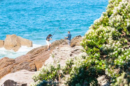 TAURANGA NEW ZEALAND - NOVEMBER 10 2012; Two men rock fishing from base of Mount Maunganui.のeditorial素材