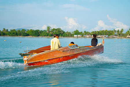 SEMPORNA iSLANDS BORNEO - MAY 12 2019; Orange boat with man and sons speeding across bay