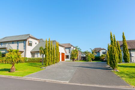 Residential neighborhood homes separated by entrance road lined with cypress trees.の写真素材
