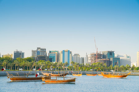 DOHA QATAR - JULY 10 2019; Dhow moored in bay with old town part of Doha citywith it's new modern...