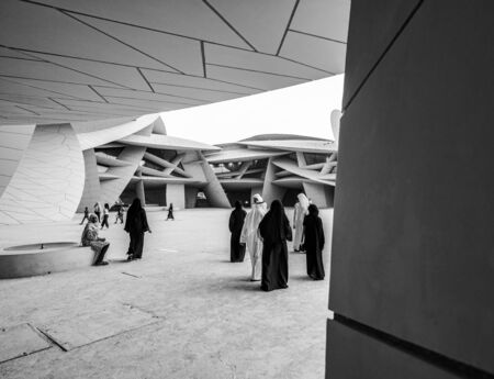 DOHA QATAR - JULY 10 2019; In black and white, people in their customary and cultural attire and the design construction features of National Museum of Qatar unusual but striking design form is inspired by desert rose crystal opened in March 2019  designeのeditorial素材