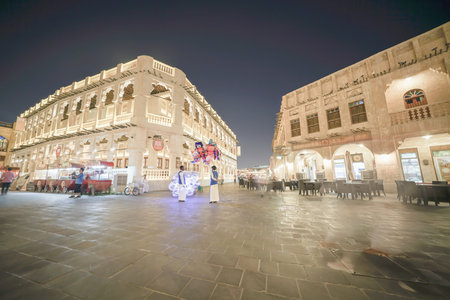 DOHA QATAR - JULY 11 2019; Night scene long exposure in Souq Waqif with people bluured in motion walking pastのeditorial素材