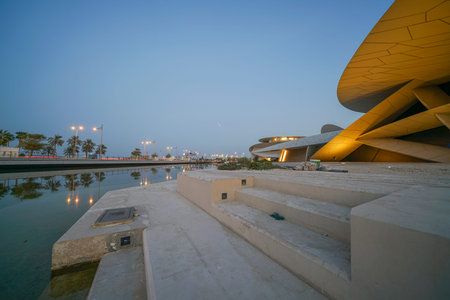 DOHA QATAR - JULY 10 2019; Exterior as lights come on National Museum of Qatar unusual but striking design form is inspired by desert rose crystal opened in March 2019  designed by architect Jean Nouvel.のeditorial素材