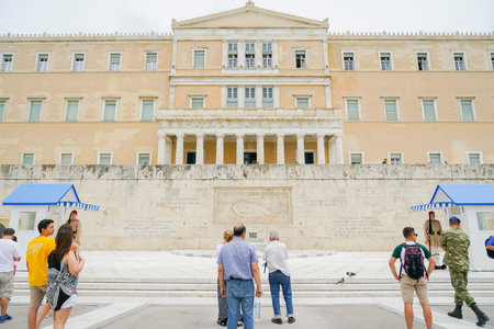 ATHENS GREECE - JULY 15 2019; Travelers watching Presidential Guard outside Presidential Mansion and wall with greek character signs guards Tomb of Unknown Soldier.のeditorial素材