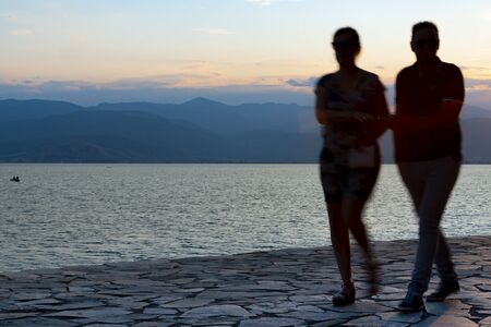 Silhouettes of couple blurred in motion as they walk along rock pathway with sun behind.の写真素材