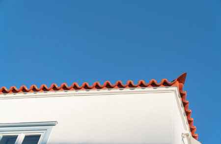 Building features, white walls, orange tiles and corner of building from low angle in characteristic...
