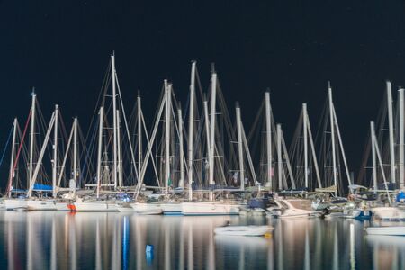 Blurry effect of long exposure Skiathos waterfront at night yacht masts caught in light, blurred while gently rocking.の写真素材