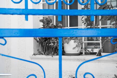 Blue wrought iron gate against monochrome window and wall. close-up.の写真素材