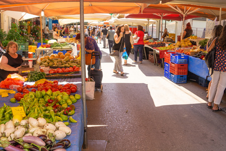 Lamia Greece - July 26 2019; People with their purchases walk between city street market  produce verdors stalls carrying their purchasesのeditorial素材