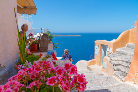Oia, Santorini, Greece - August 7 2019; View across Mediterranean from h]illside homes and buildings in whitewashed with splashes of color in traditional Greek Island styleのeditorial素材