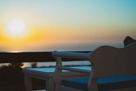 Seat and table in foreground of warm Mediterranean sunset in faded vintage tones.の写真素材
