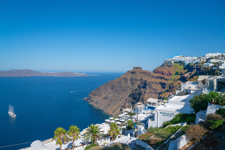 Santorini Greece - August 8 2019; Severe rocky hillsides and headland on Greek Island with characteristic whitewashed restauransts and accomodationのeditorial素材